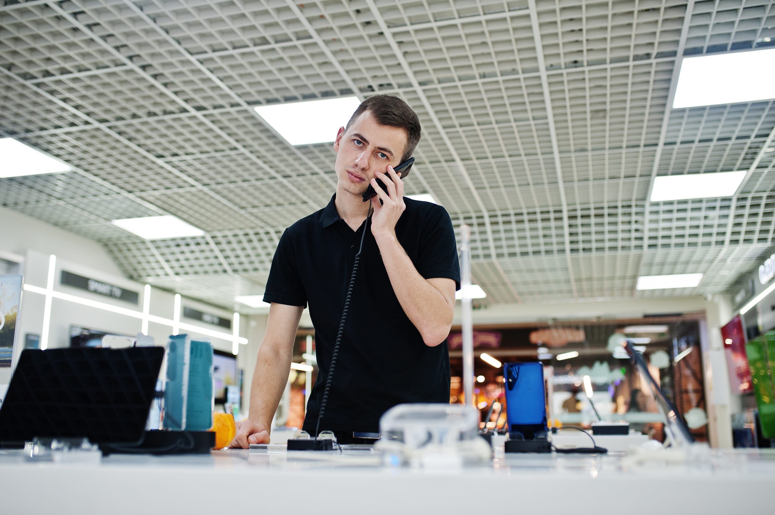jovem funcionário de loja de telefonia atende cliente no telefone