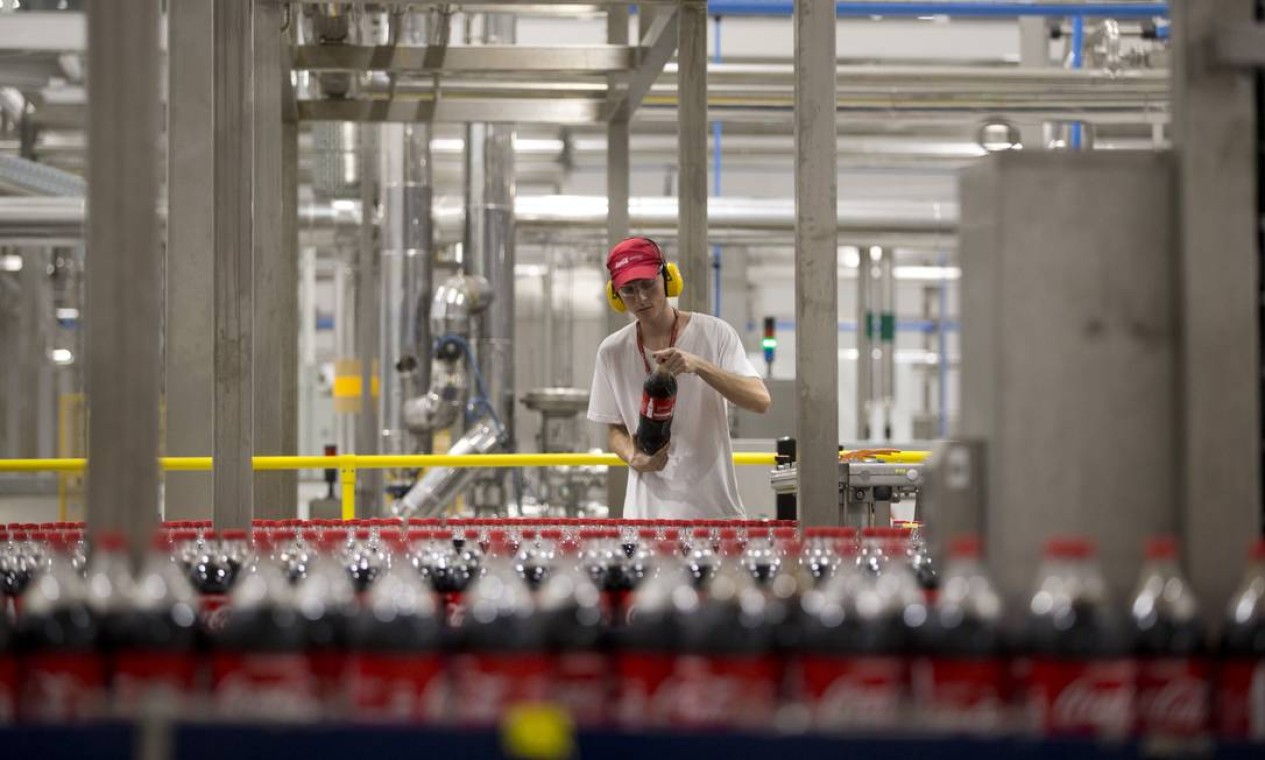 Jovem trabalha em uma fabrica brasileira da Coca-Cola
