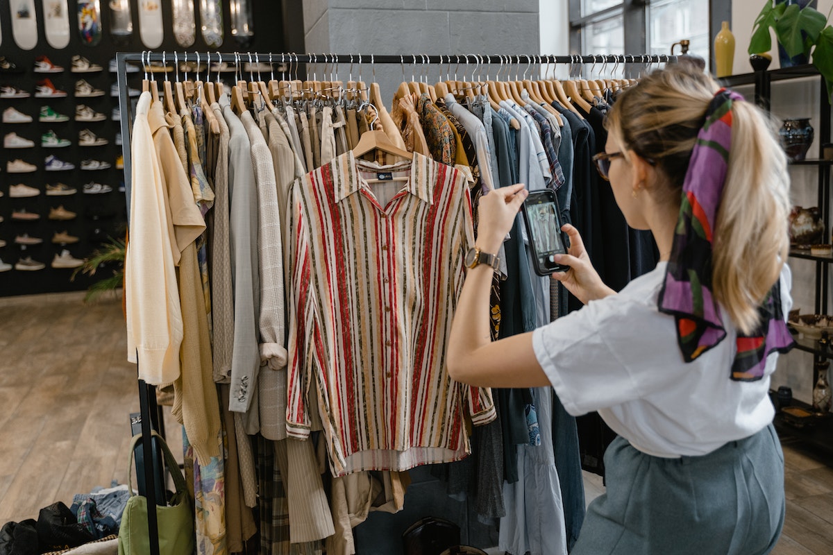Imagem de uma Jovem Aprendiz Renner 2024 na loja tirando foto de algumas roupas