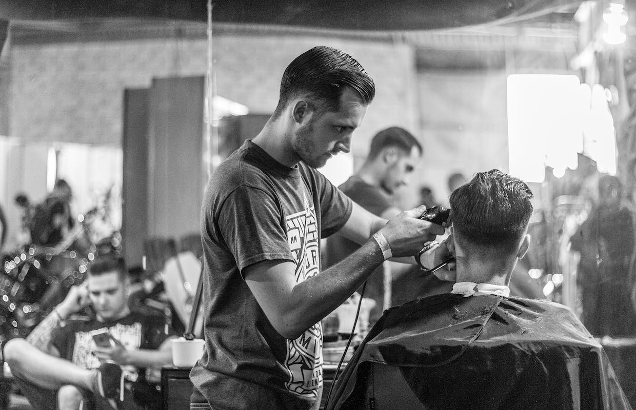 Um barbeiro está cortando o cabelo de um cliente