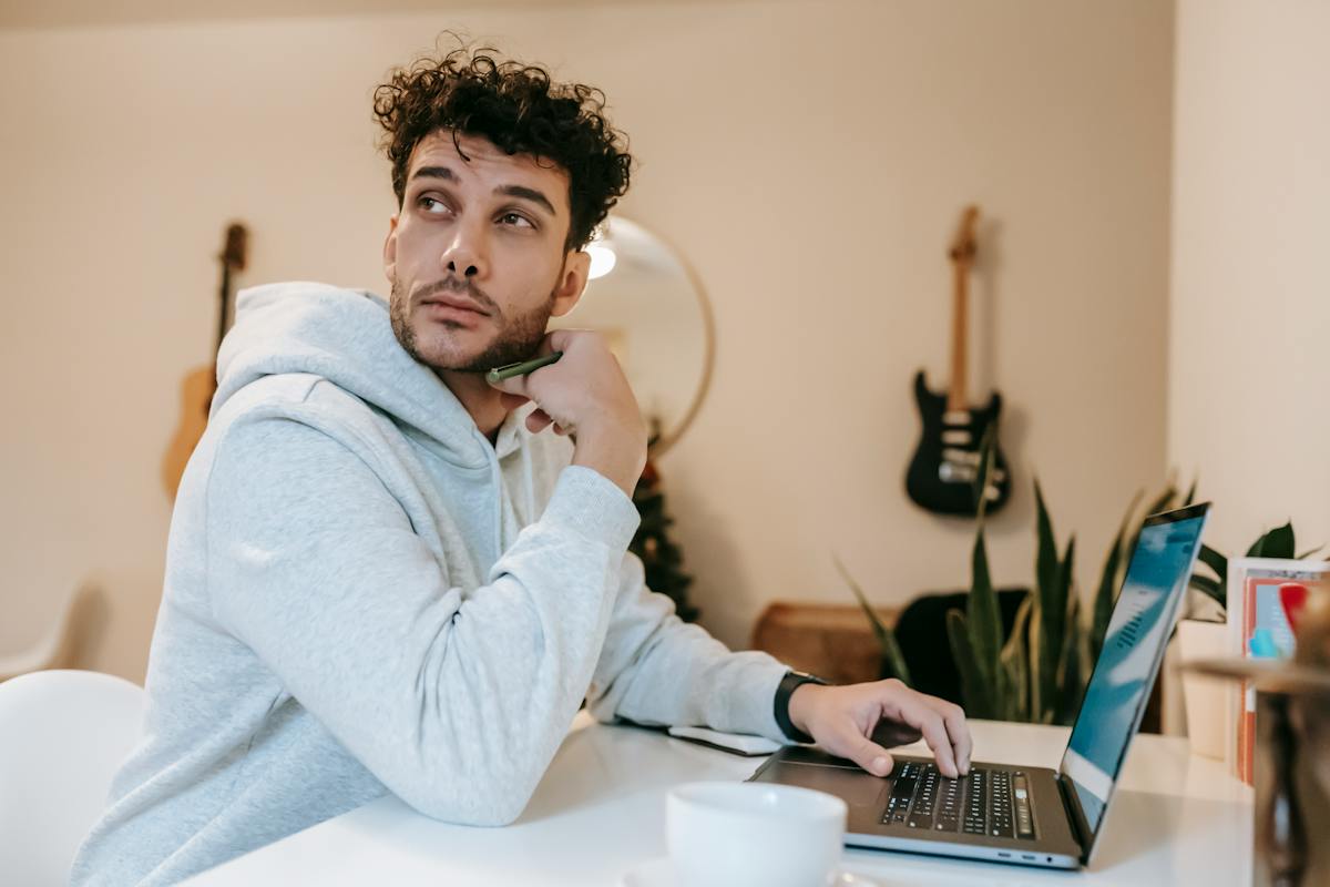 Um home está sentado na frente do computador, olhando para o lado e pensando se Jovem Aprendiz Tem Direito a Décimo Terceiro