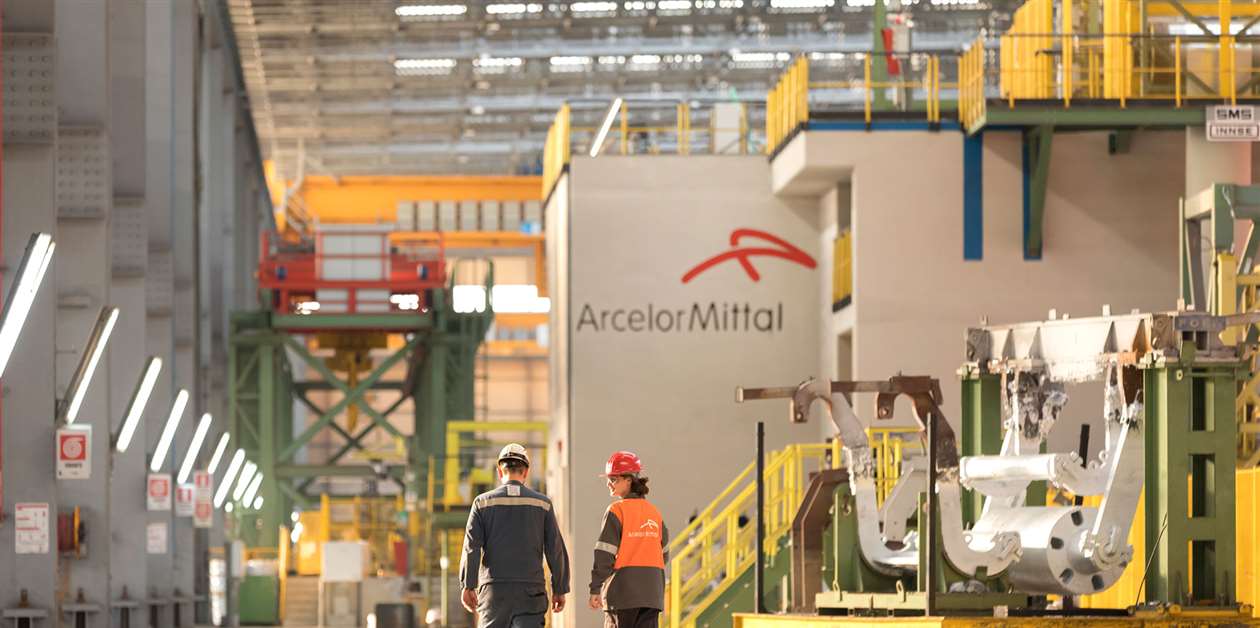 Colaboradores da ArcelorMitta caminham por uma das unidades da empresa 