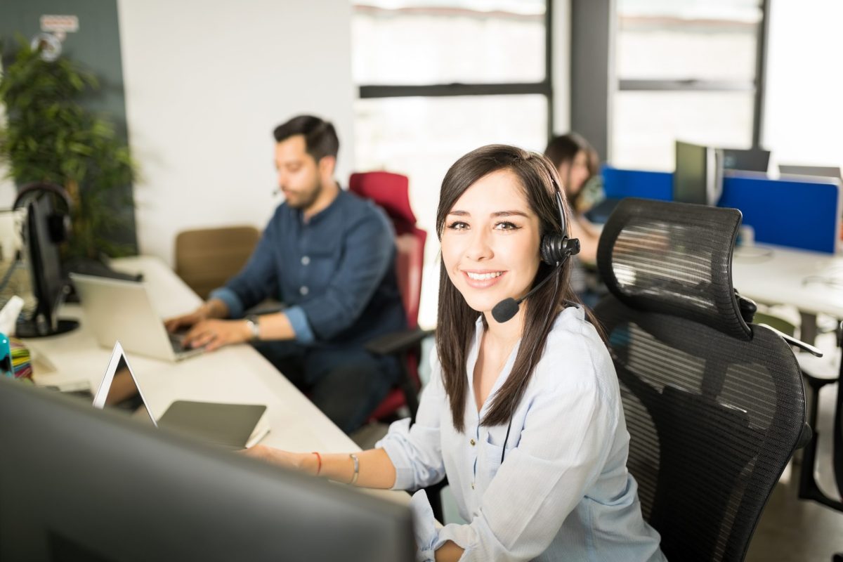 jovem telemarketing posa sorridente em sua mesa de trabalho